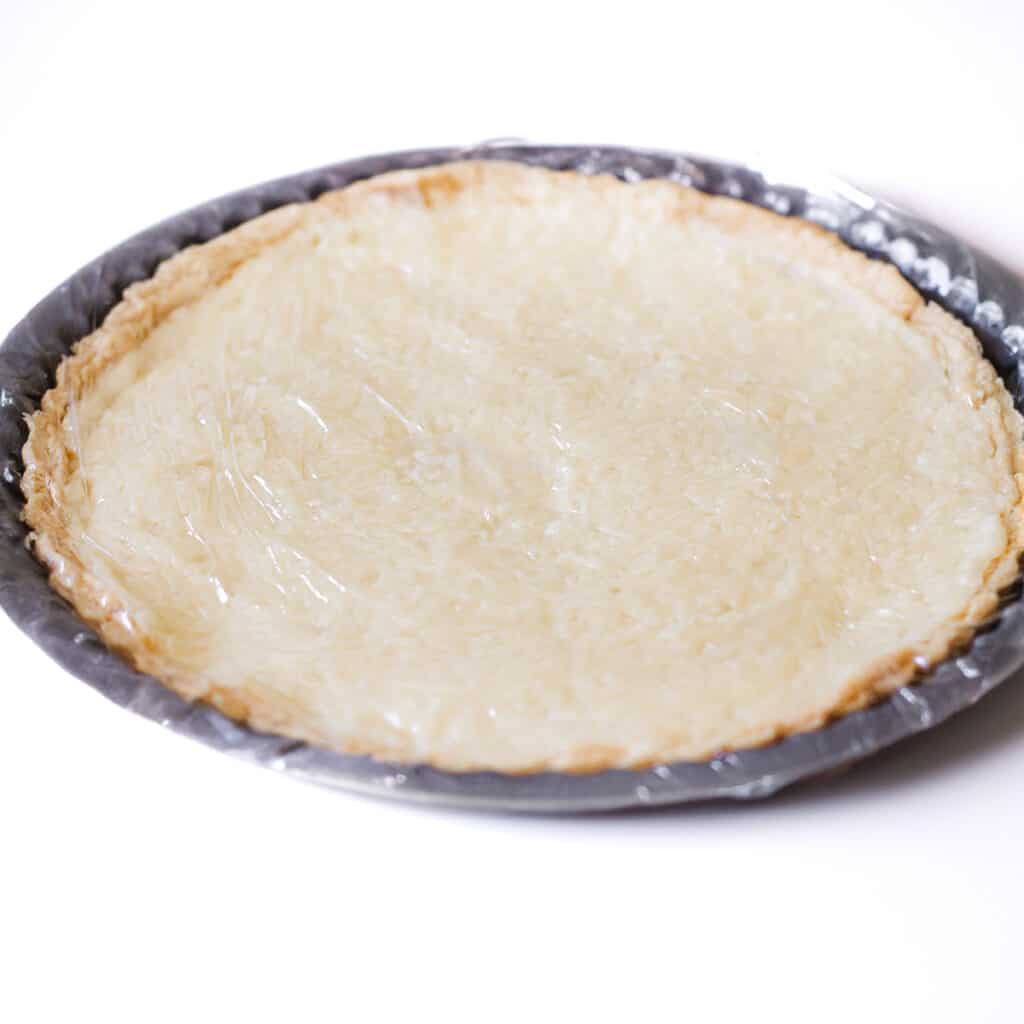 the set pie in a pie pan covered with plastic wrap.