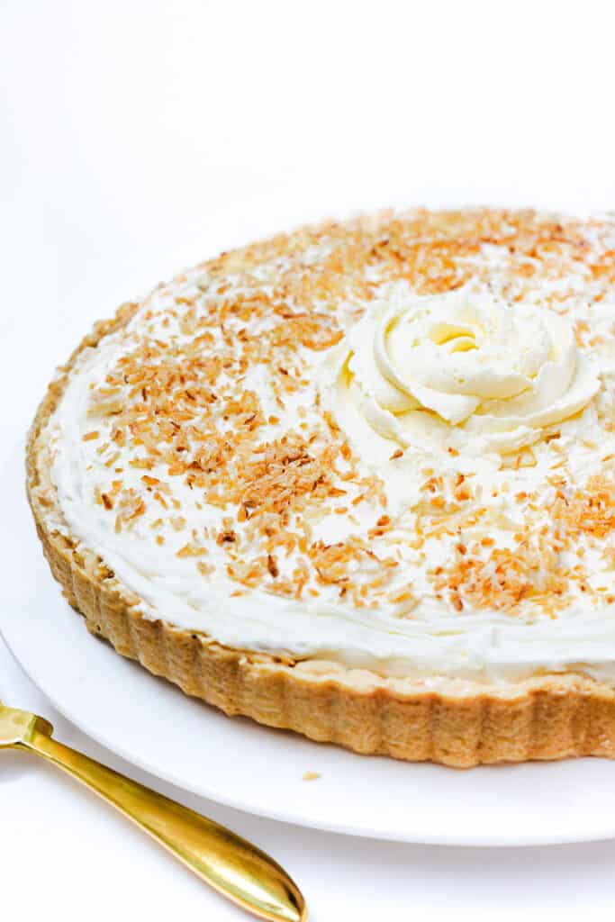 the assembled coconut cream pie on a plate with a pie server next to it