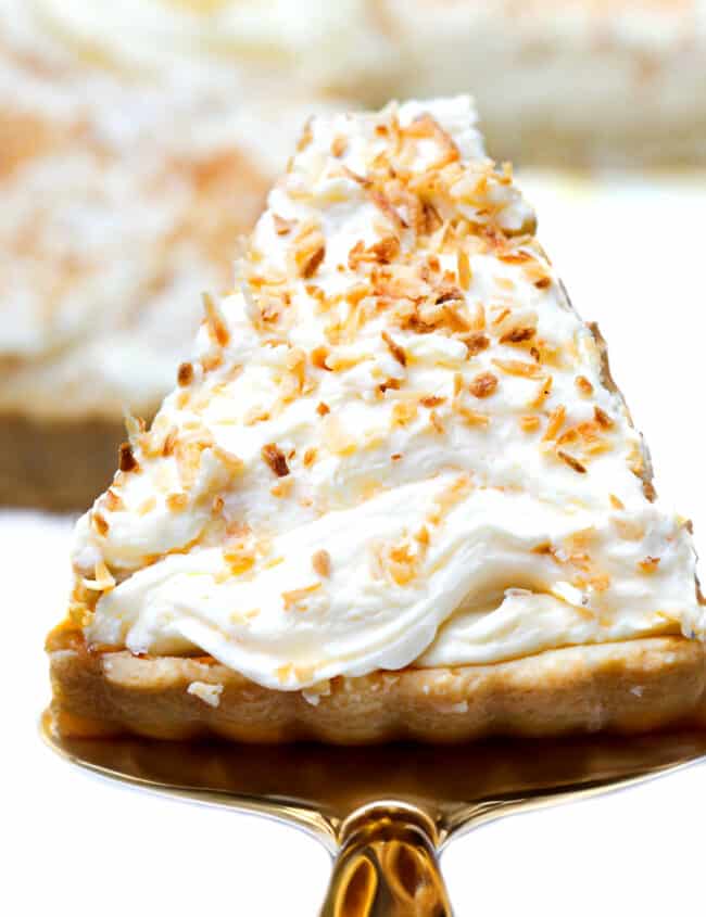 An overhead detailed shot of a slice of coconut cream pie garnished with toasted coconut flakes being served.