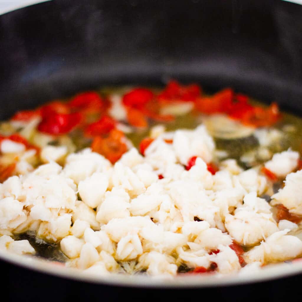 the crab peppers and wine cooking in the pan with the garlic.