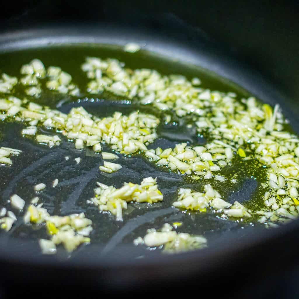a pan with garlic cooking in olive oil