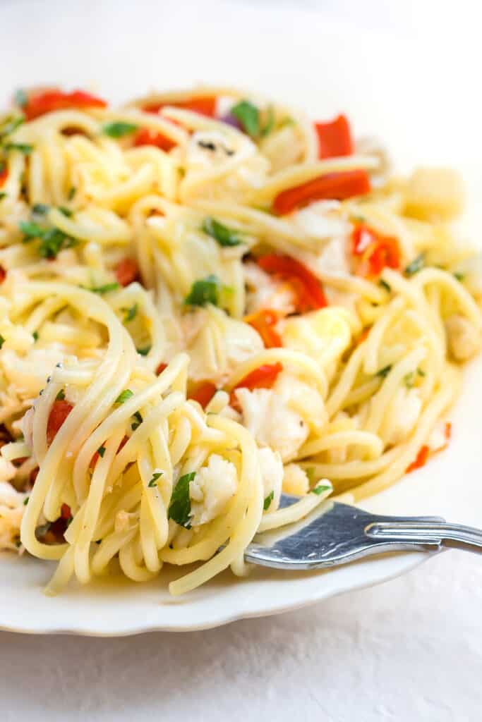the Crab Pasta on a white plate with a fork twirling the spaghetti laying on the plate
