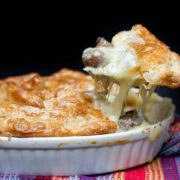 A close up of a spoonful of cheesy chicken mushroom pie being taken from a dish