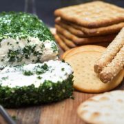 A close up of various crackers with a garlic and herb cream cheese log