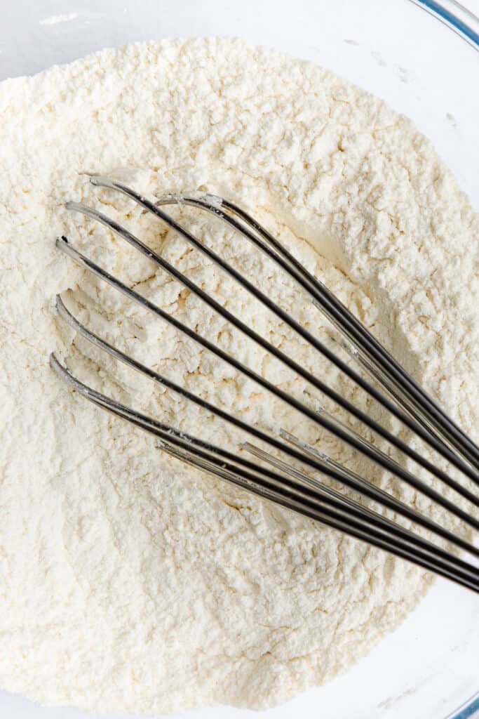 a whisk in a bowl of the dry ingredients for scotch pancakes.