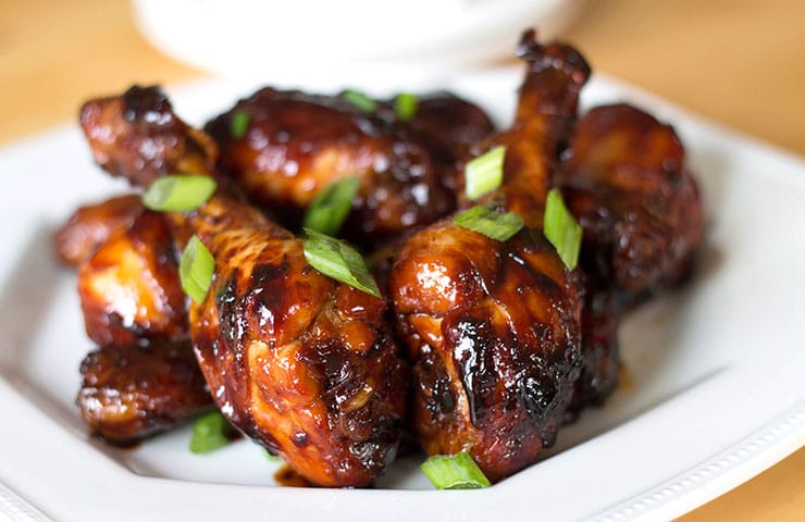 A plate of sticky Chinese chicken with chopped green onions