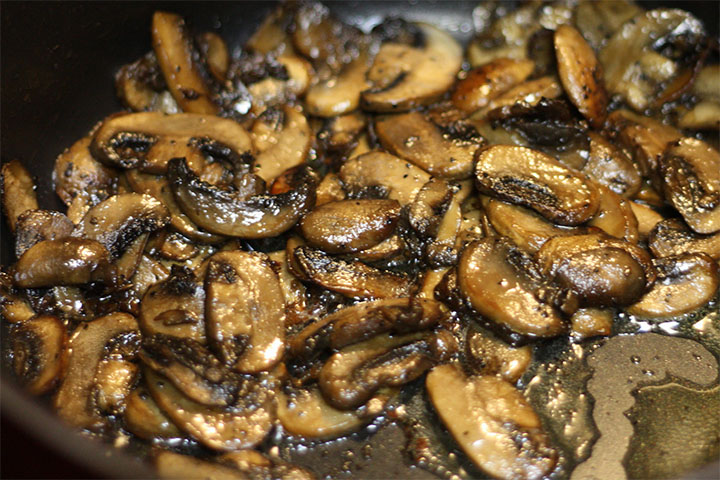 Sliced mushrooms cooked in the pan with the shallots and garlic
