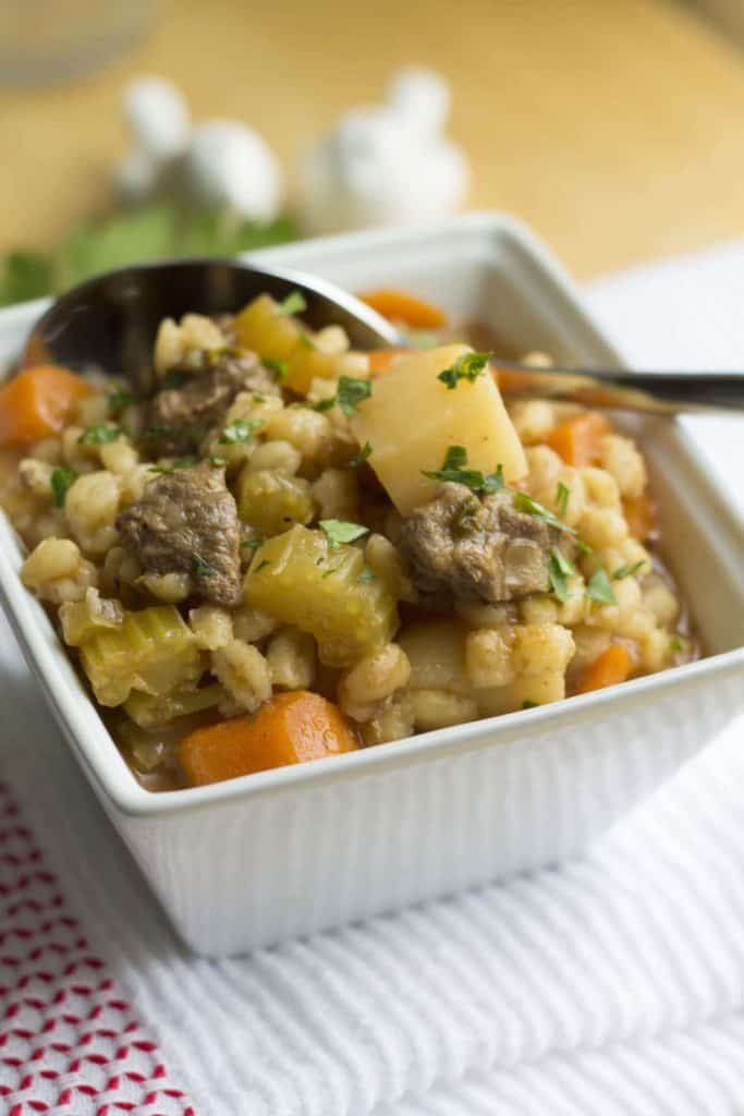 Beef and Barley Soup piled high in a bowl with a spoon in it