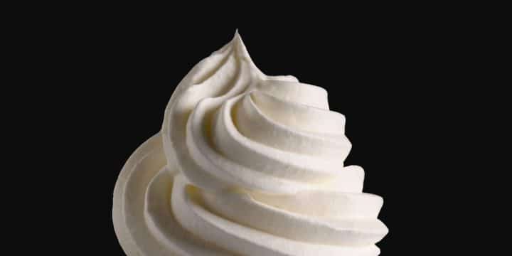 A close up of a swirl of whipped cream with a black background