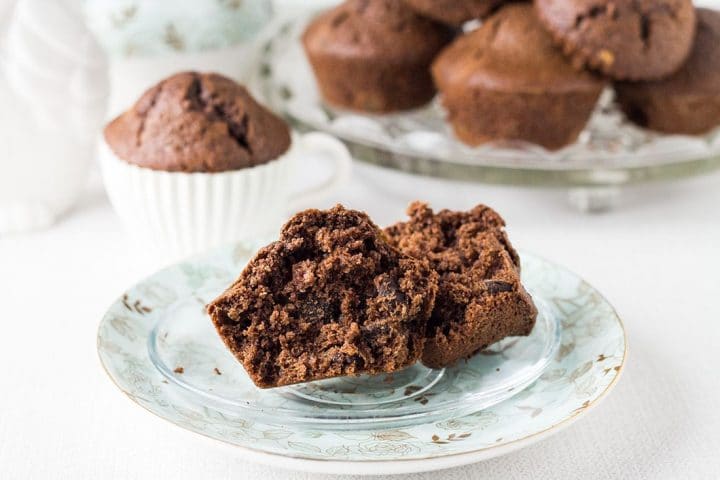 a Double Chocolate Chip Muffin on a plate broken in half to show the chocolate chips inside