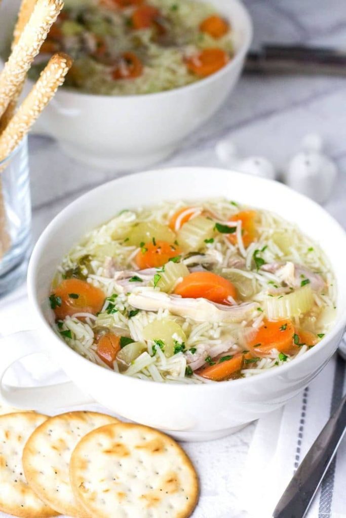 a bowl of chicken noodle soup ready to serve with crackers