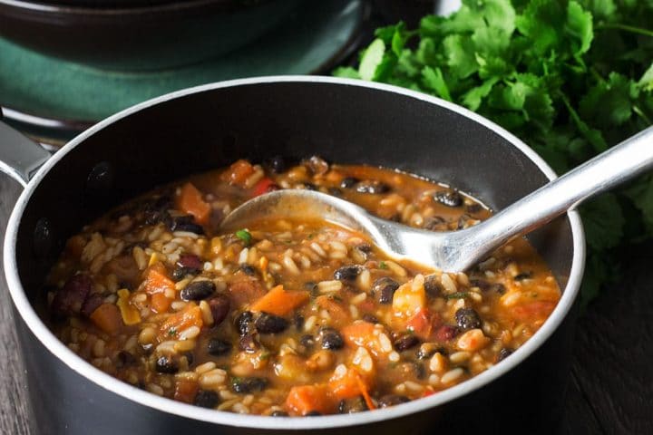 Mexican Rice & Bean Soup in a large pot with a ladle scooping the soup
