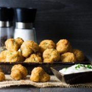Side view of Baked Breaded Garlic Mushrooms in a black bowl served with a sour cream dip