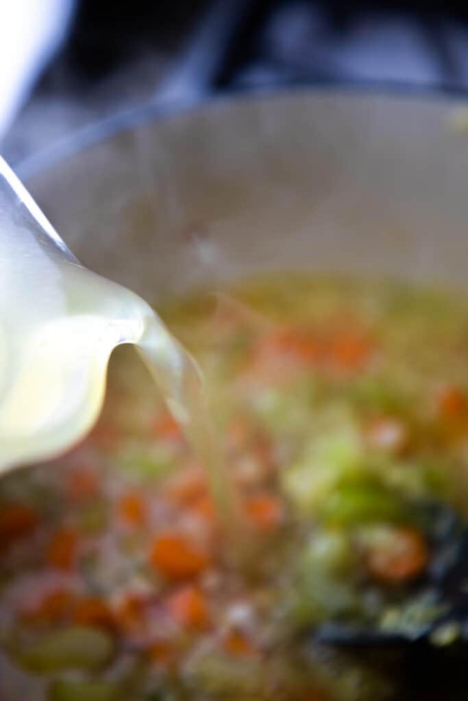 chicken stock being pored into the pot