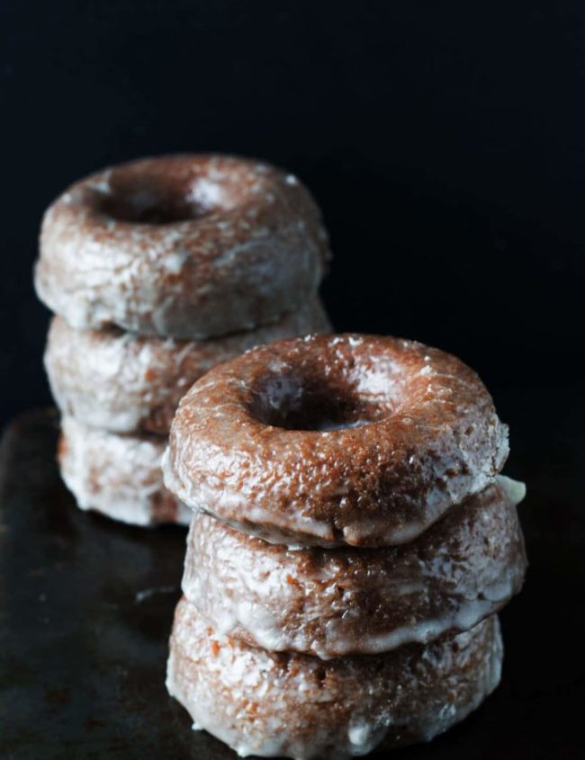 Two stacks of freshly baked chocolate glazed doughnuts.