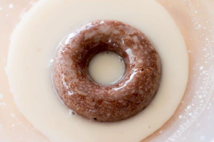 a backed doughnut sitting in the bowl of glaze