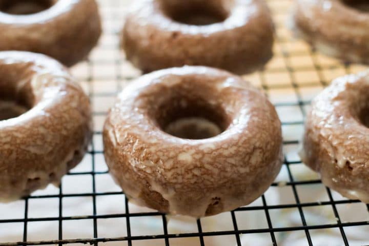 The glazed doughnuts sitting on the cooling rack dripping with glaze