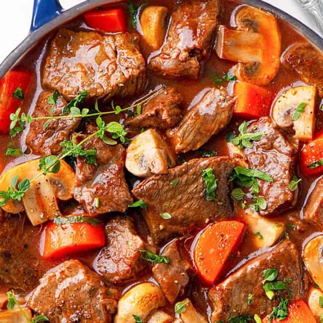 a big pot of beef stew with a spoon next to it