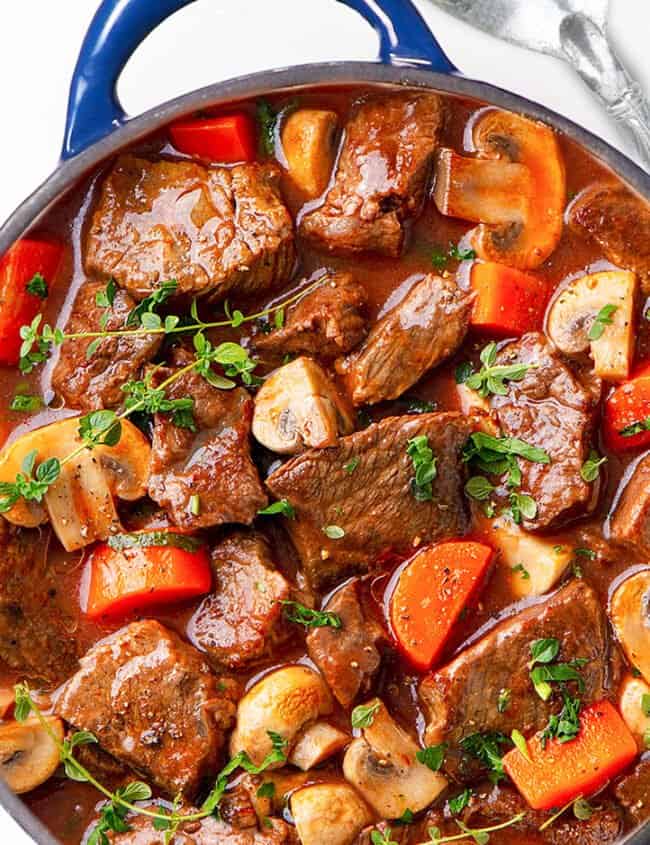 a big pot of beef stew with a spoon next to it