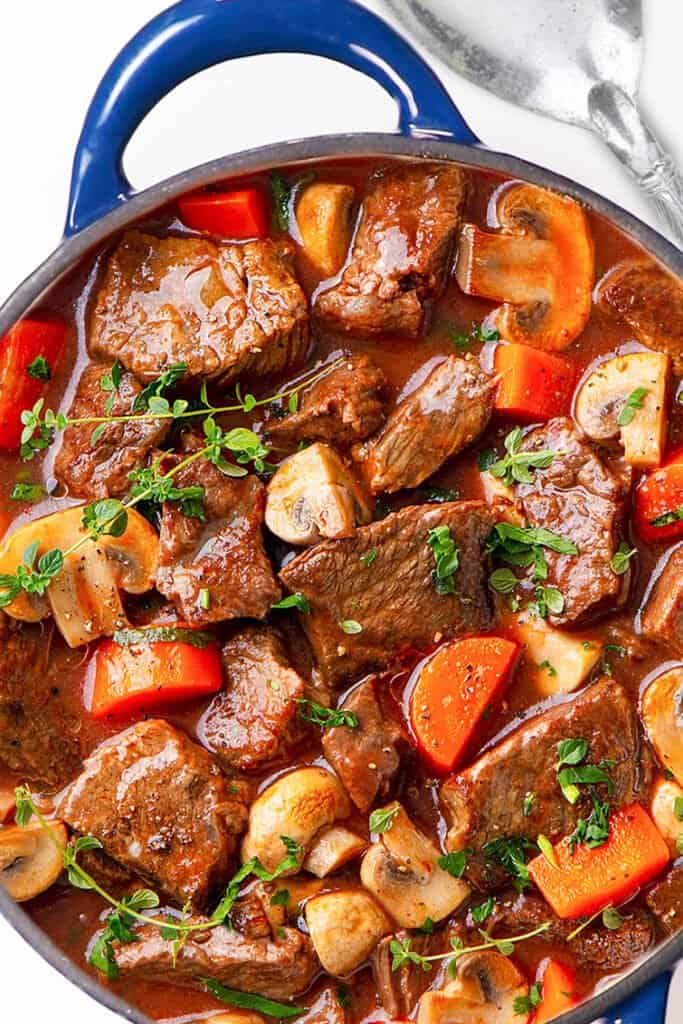 a big pot of beef stew with a spoon next to it