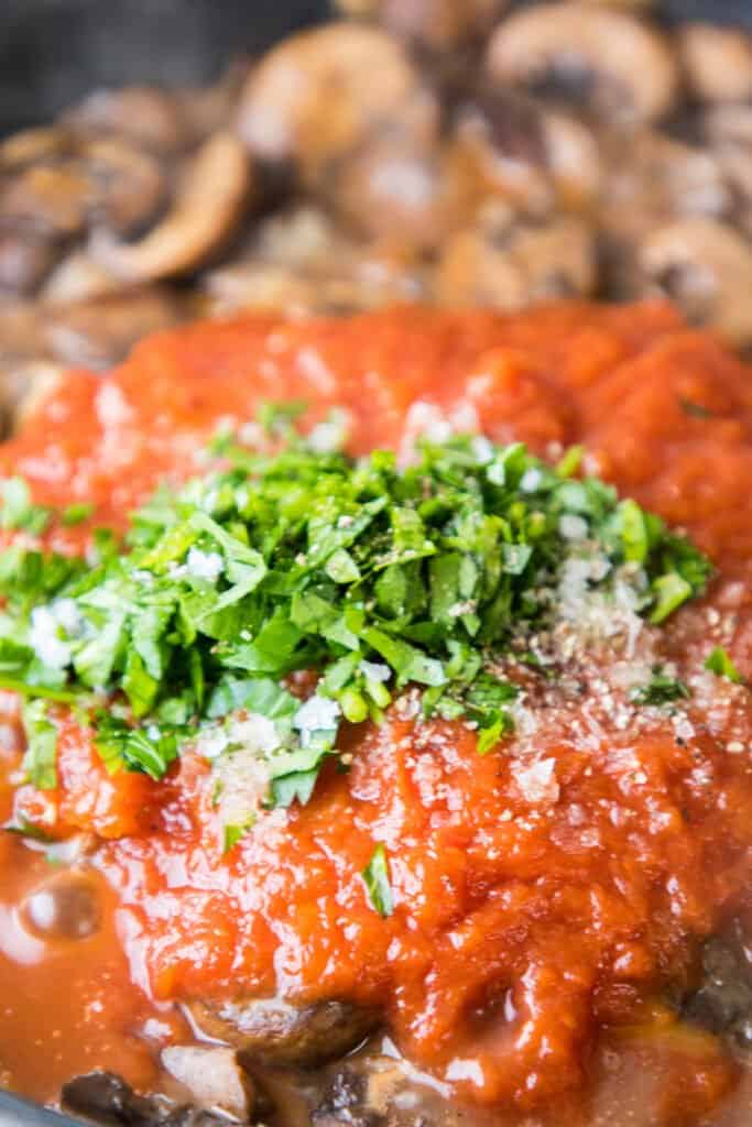 tomato sauce and herbs in a pan with mushrooms and beef