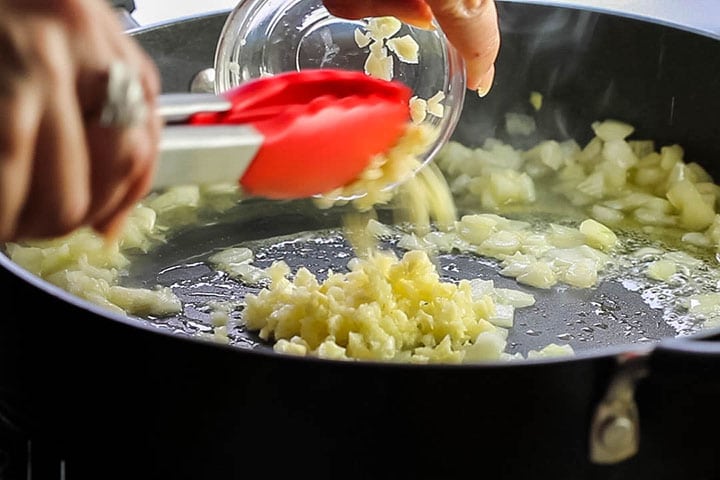 The garlic being added to the pan with the onions