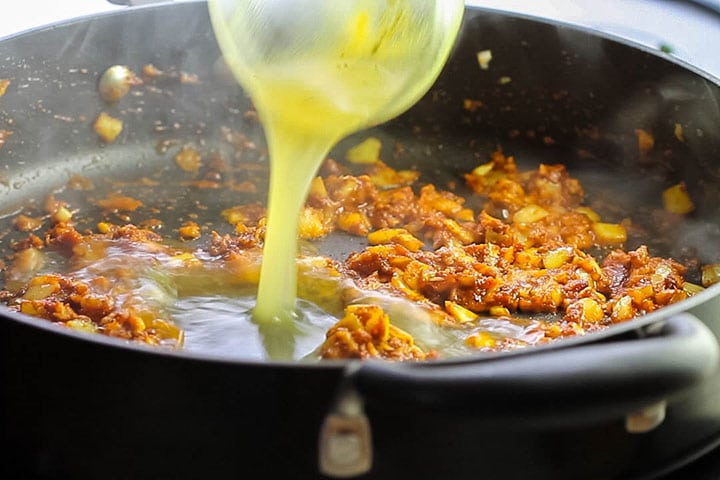 The stock being poured into the pan