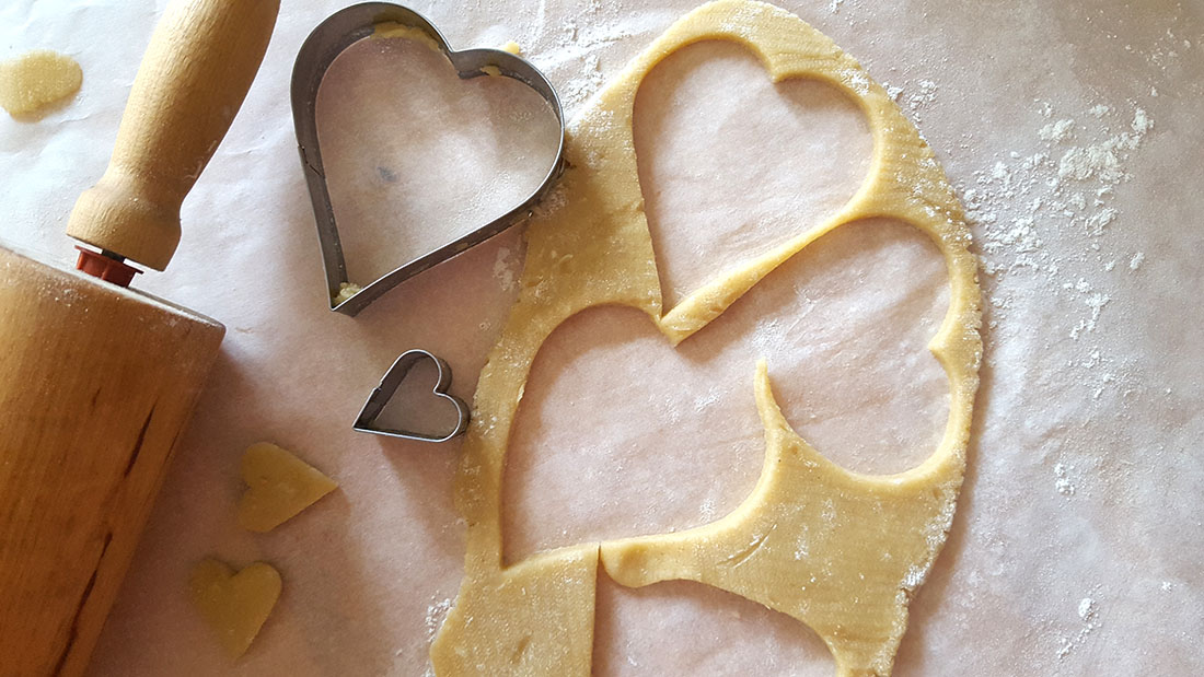 Cookie cutter with dough with heart shapes cut out