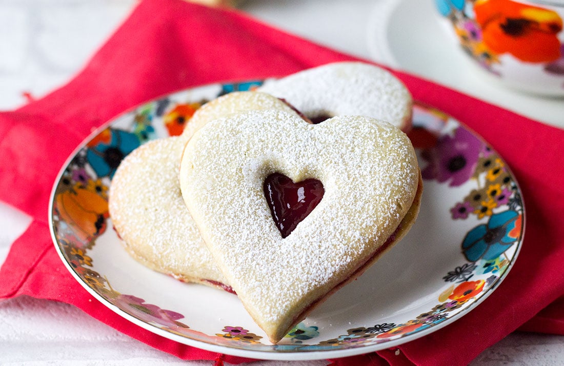 A close up of raspberry butter cookies dusted with confectioners sugar