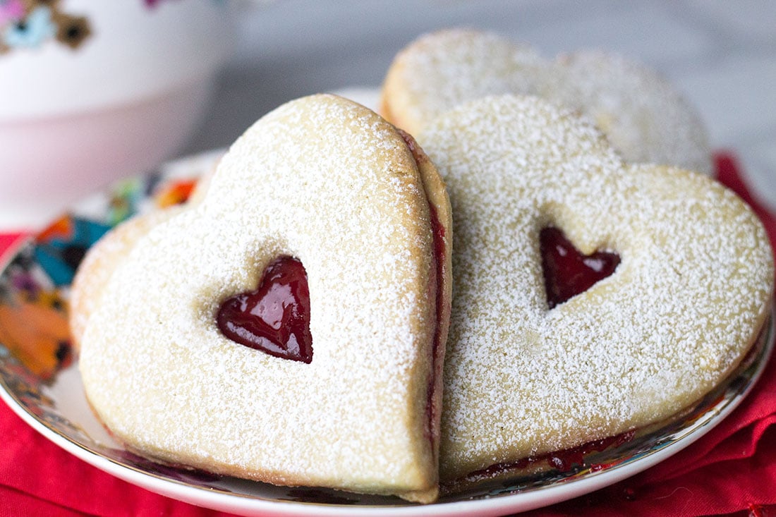 a close up of heart shaped raspberry butter cookies on a plate