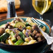 A close up of a bowl piled high with pasta and roasted vegetables