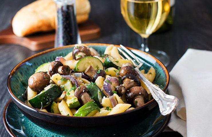 A close up of a bowl piled high with pasta and roasted vegetables 