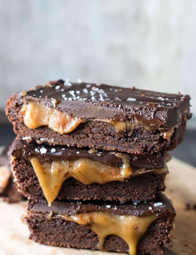 Cut slices of the Salted Chocolate & Caramel Bars stacked and piled on each other with the caramel oozing out and the salt on top