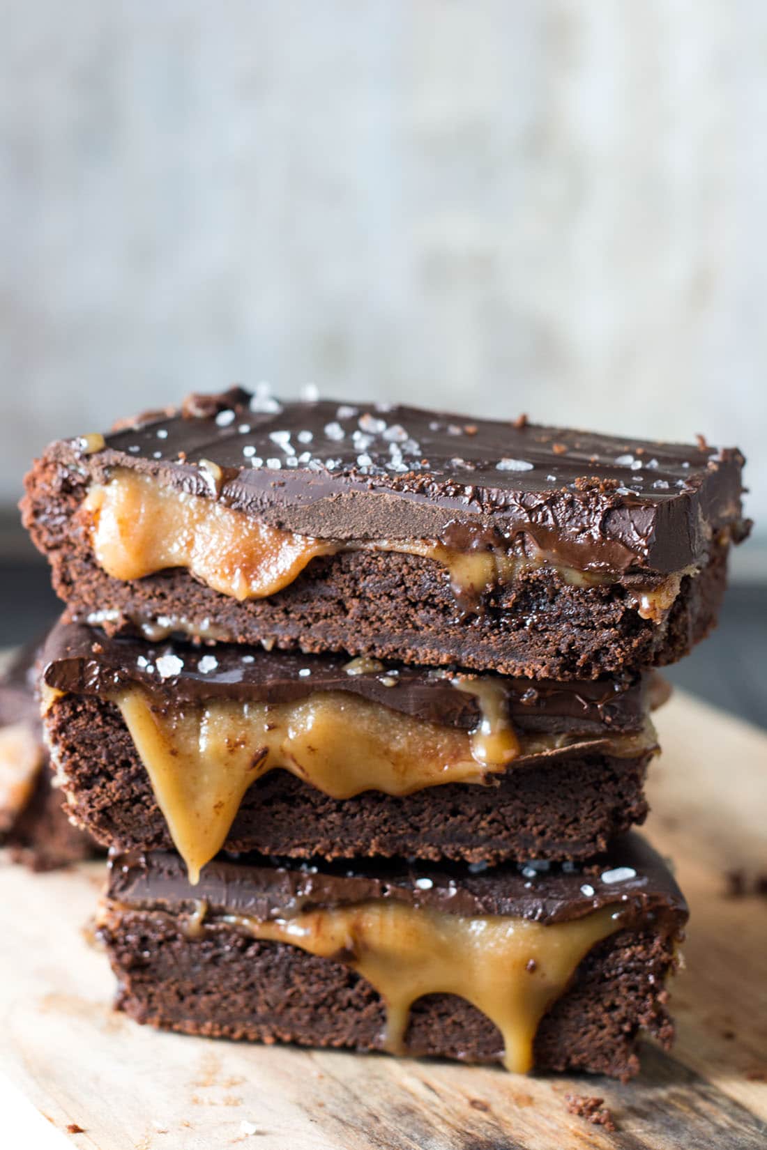 Cut slices of the Salted Chocolate & Caramel Bars stacked and piled on each other with the caramel oozing out and the salt on top