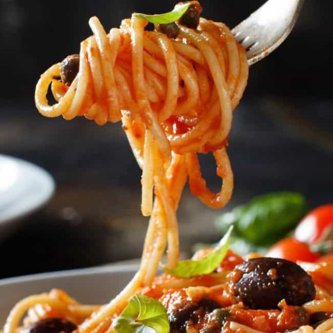 Spaghetti Alla Puttanesca twirled on a fork over the plate
