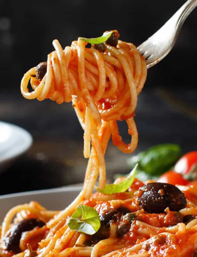Spaghetti Alla Puttanesca twirled on a fork over the plate