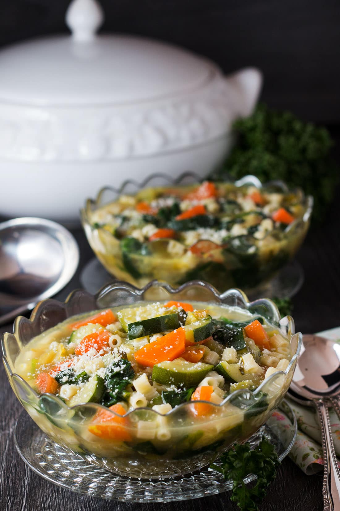 Two bowls of Spring Vegetable Soup in glass bowls with cultery