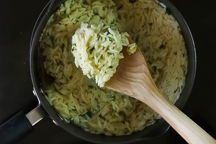 The rice pilaf being stirred with a wooden spoon