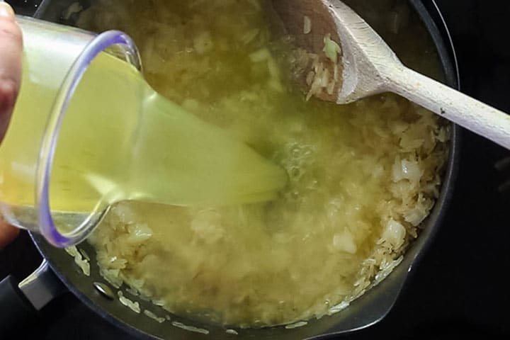 Stock being poured into the pot with the rice mixture