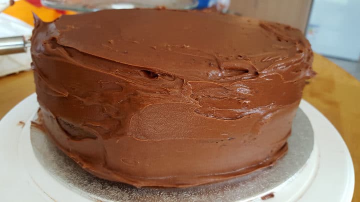 A close up of a piece of chocolate cake on a plate covered in frosting