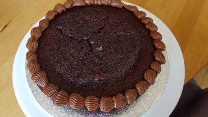 A piece of chocolate cake on a plate, with Chocolate frosting around it