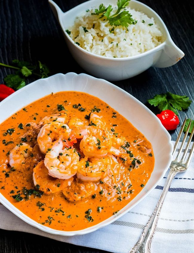 Quick and Easy Thai Red Curry in a white plate with rice and herbs in the background