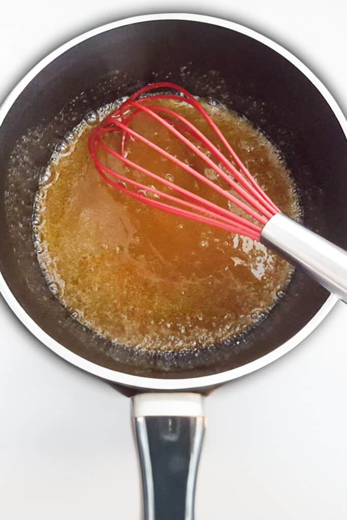 a pot with the butter and sugar mixture melted together with a whisk.