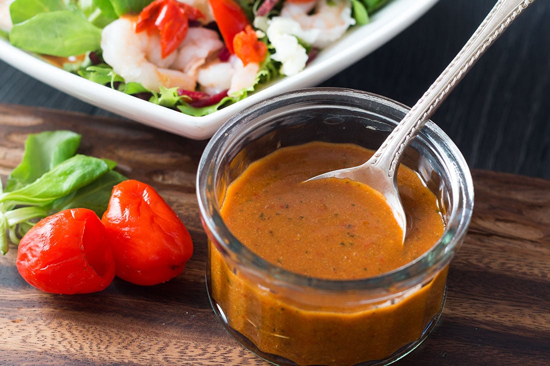 A ramekin filled with Catalina style peppadew salad dressing with a spoon