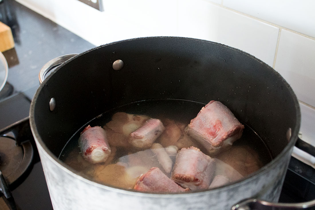 ox tail boiling in a large pan with stock