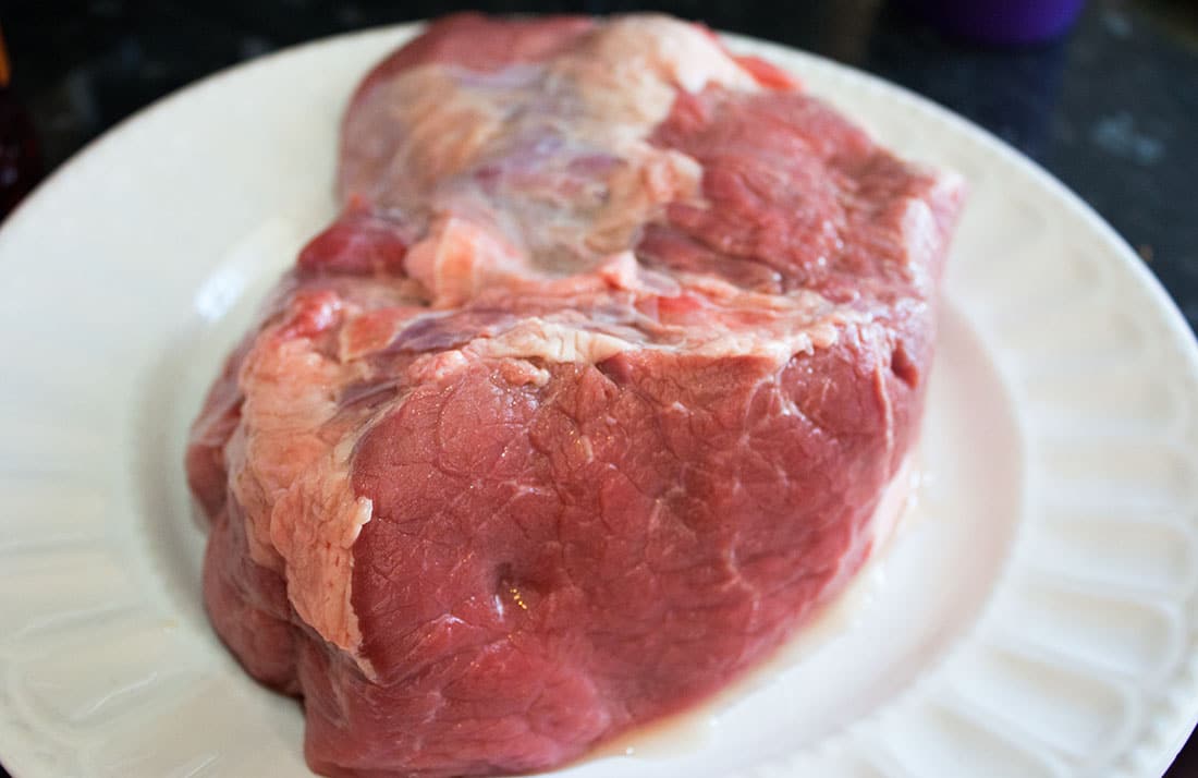 a raw joint of beef on a white plate