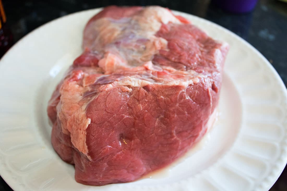 A large piece of raw beef on a white plate