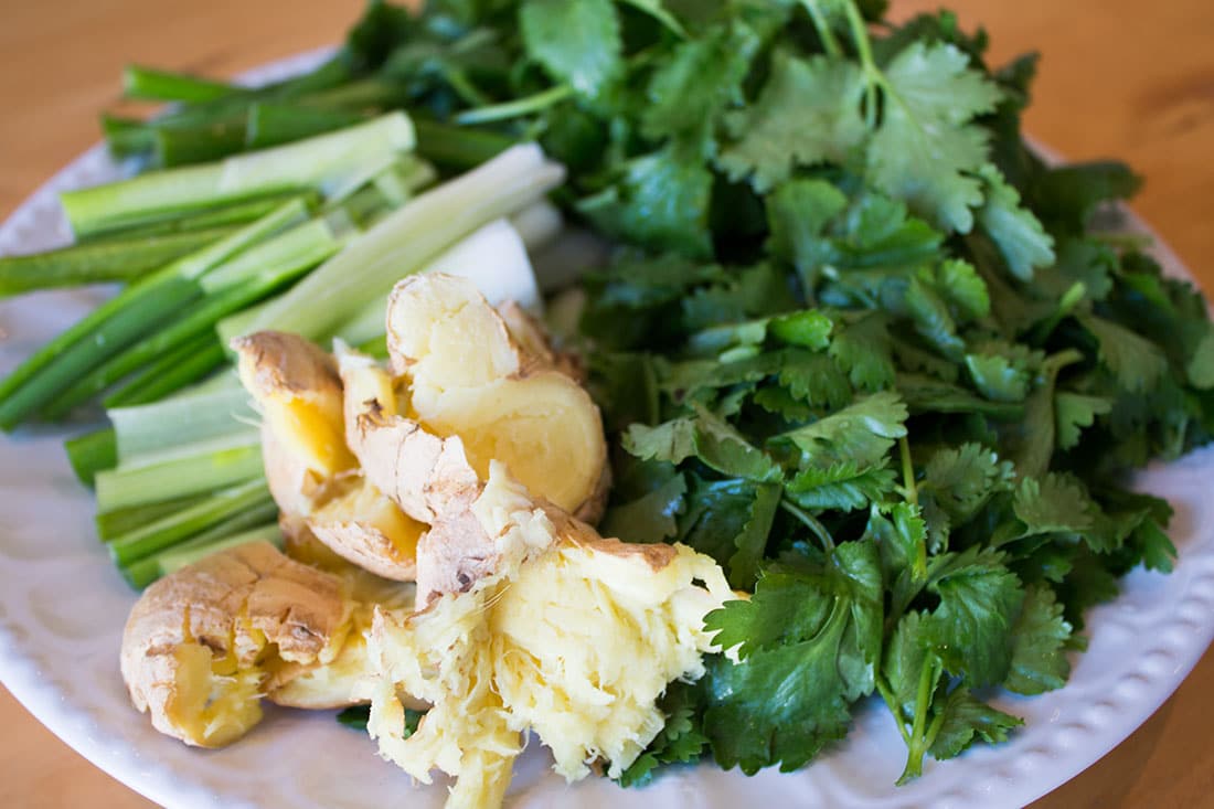  chopped spring onions, fresh herbs and crushed ginger root on a white plate