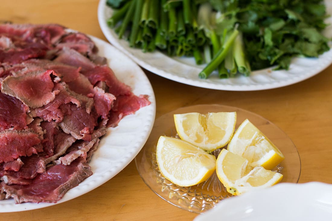 three plates of food with ingredients for Vietnamese beef noodle soup