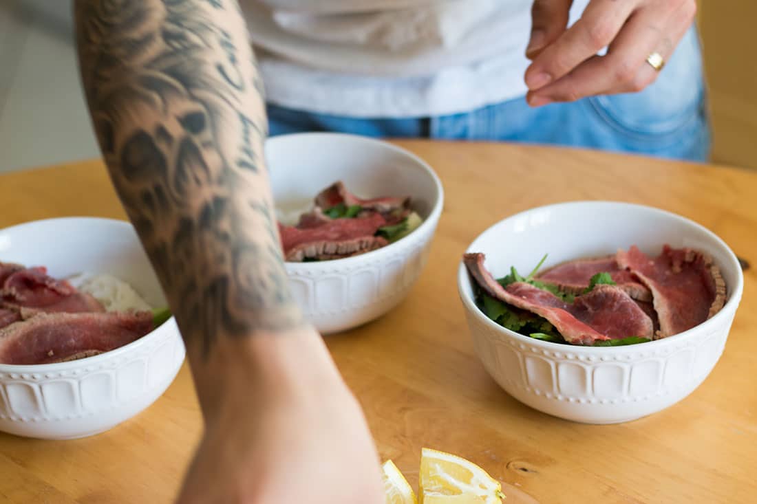 Tuan preparing three bowls with sliced beef ready for the soup